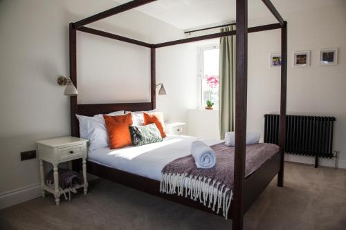 盖特豪斯厄夫弗利特Luxury Scottish Hot Tub Getaway的一间卧室配有带橙色枕头的大天蓬床