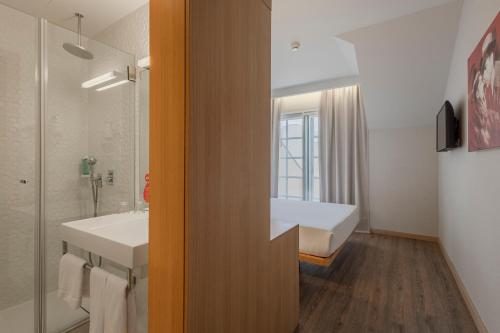 波尔图Moov Hotel Porto Centro的一间带两个盥洗盆、浴缸和窗户的浴室