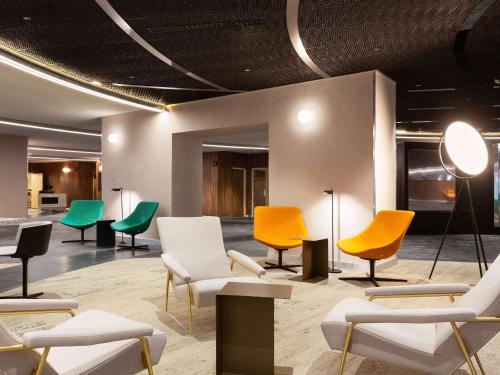 巴黎Pullman Paris Montparnasse的一间设有五颜六色的椅子和桌子的等候室