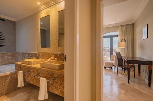 蓬塔卡纳Sports Illustrated Resorts Marina and Villas Cap Cana - All-Inclusive的一间带两个盥洗盆、一个浴缸和一张桌子的浴室