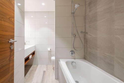 温特和克Hilton Garden Inn Windhoek的带浴缸、卫生间和淋浴的浴室。