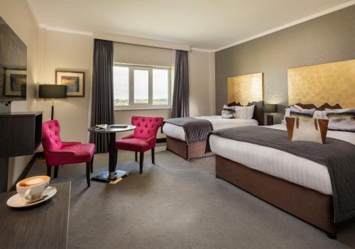 卡洛卡罗泰尔伯特酒店的酒店客房带两张床和一张桌子以及椅子。