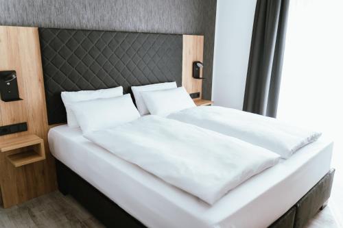 巴特德里堡Hotel am Park Bad Driburg的一张带黑色床头板和白色枕头的白色床