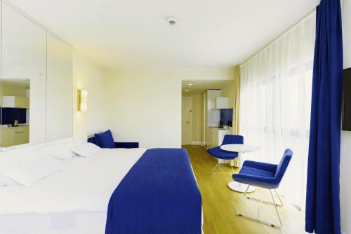 巴统Elite Class Sea View Aparthotel In Orbi City Batumi的一间卧室配有一张床、两把椅子和一张桌子