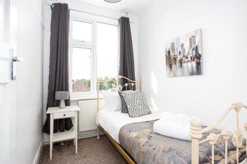 滨海绍森德Large 4 Bed in Southend, near shops/cafés/beach!的一间小卧室,配有床和窗户