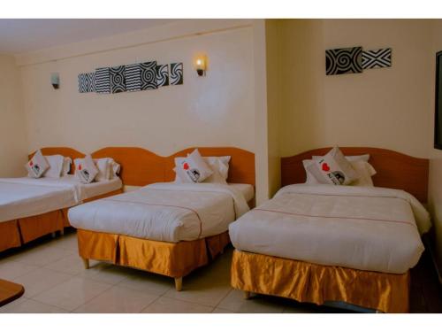 基加利Igitego Hotel Remera的酒店客房,配有两张带白色床单的床