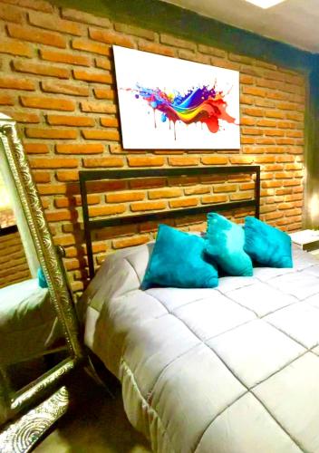 小米内拉尔Cabaña Hermosa Bosque Fraccionamiento Privado的一间卧室配有一张带蓝色枕头的床铺,靠砖墙