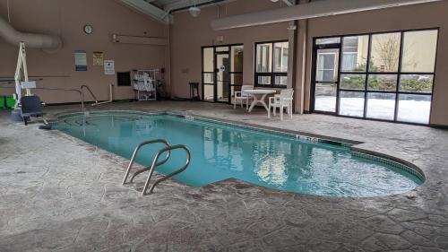 班戈Bangor Suites Airport Hotel的大楼内带桌椅的大型游泳池