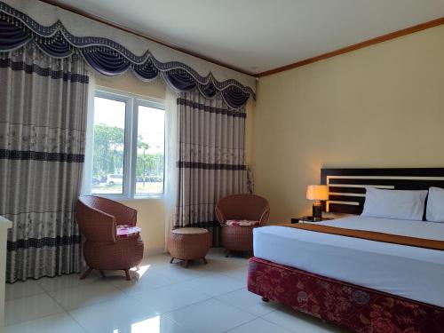 BongomeonH. V Hotel Bandara Gorontalo的一间卧室配有一张床、两把椅子和一个窗户