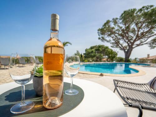 圣马克西姆Villa Cacharel - MAX230 by Interhome的一张桌子上摆放着一瓶葡萄酒和酒杯