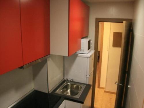 马德里Hochwertige Ferienwohnung im Grüngürtel der Stadt的一个带红色橱柜和水槽的小厨房
