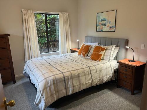 陶波Acacia Views - Acacia Bay Holiday Home的一间卧室配有带橙色枕头的床和窗户。