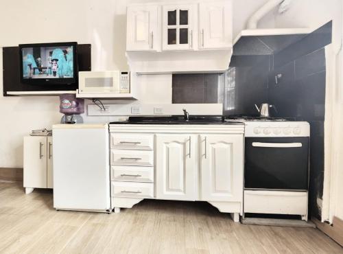 马丁内斯Jazmines Apart的厨房配有白色橱柜和黑炉。