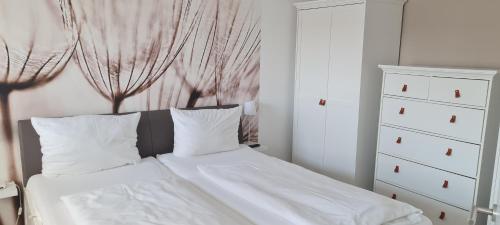 诺德奈Dünenrose Seegras Nr 41的一间卧室配有一张带白色床单的床和梳妆台。