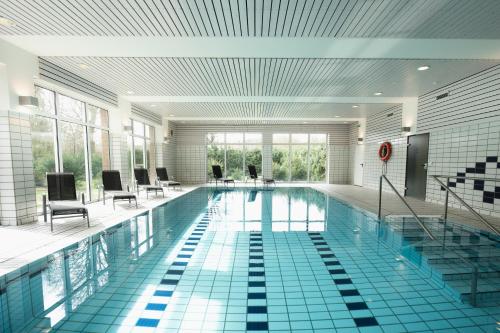 巴特德里堡Hotel am Park Bad Driburg的大楼内带桌椅的大型游泳池