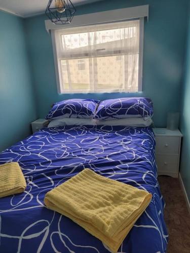 曼斯利Chalet 69的蓝色卧室设有一张带紫色床单的床和窗户