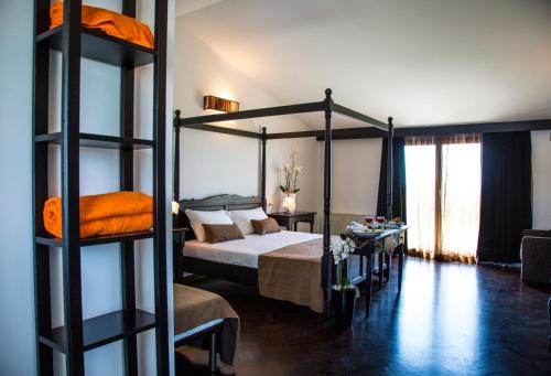 希克利Zeta Resort Donnalucata的一间带天蓬床的卧室和一间带桌子的房间