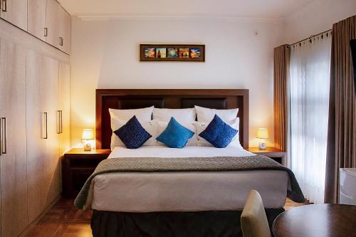 MatolaPlatinum Lodge的一间卧室配有一张带蓝色枕头的大床
