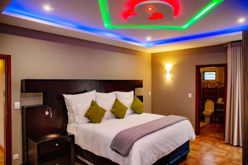 MatolaPlatinum Lodge的酒店客房的天花板上设有 ⁇ 虹灯标志的床。