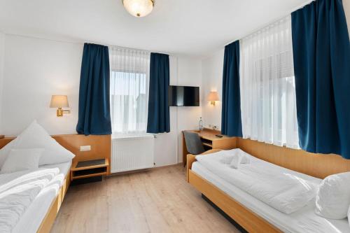 腓特烈港Hotel Garni Traube的酒店客房,设有两张床和蓝色窗帘