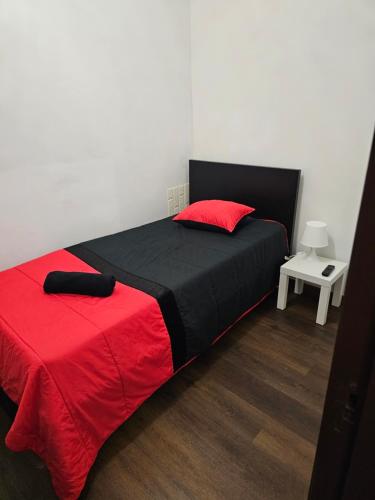 里奥廷托雷斯公寓的一间卧室配有一张带红色和黑色毯子的床