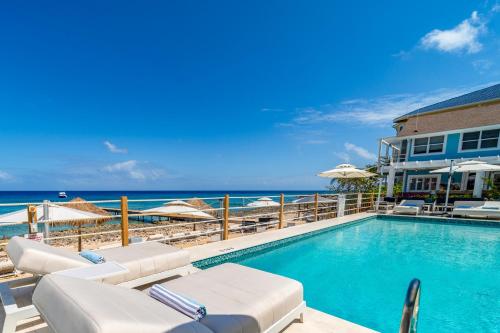 西湾Cobalt Coast Resort的一个带椅子和遮阳伞的游泳池以及大海
