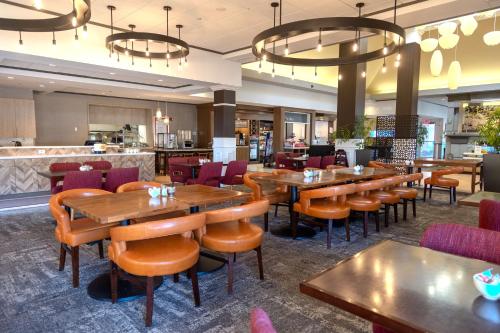 佳侬斯堡匹兹堡/南岬希尔顿花园旅馆的一间带木桌椅的餐厅和一间酒吧