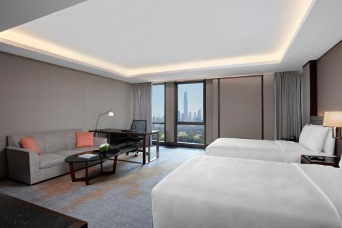 深圳金茂深圳 JW 万豪酒店的酒店客房配有一张床、一张沙发和一张书桌。