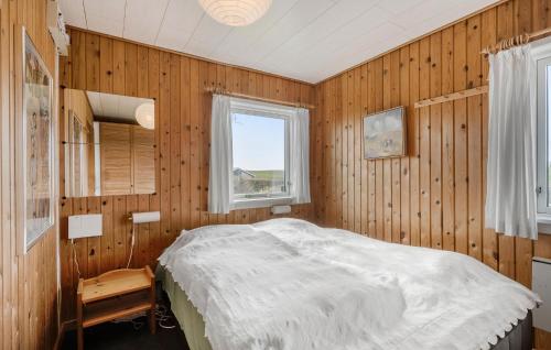 博恩瑟Gorgeous Home In Bogense With Kitchen的一间卧室设有木墙和一张带窗户的床