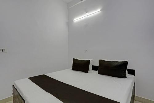 阿里格尔OYO HOTEL KAVYA RESIDENCY的白色客房的一张床位,配有黑色枕头