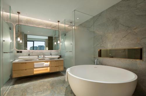 三亚三亚希尔顿花园酒店的浴室设有2个水槽、浴缸和镜子