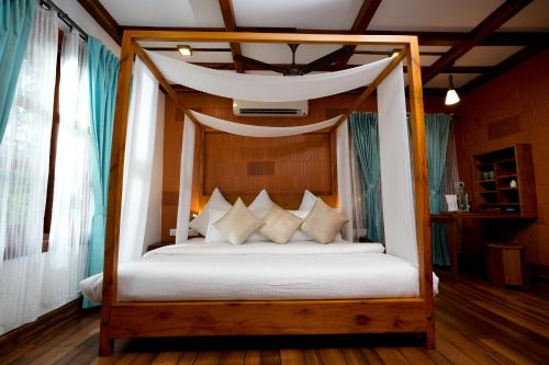 库玛拉孔Little Chembaka的卧室配有带白色床单和枕头的天蓬床。