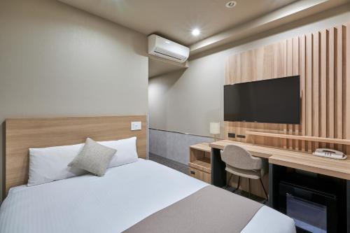 东京东京神保町芬迪别墅酒店的一间卧室配有一张床、一张书桌和一台电视。