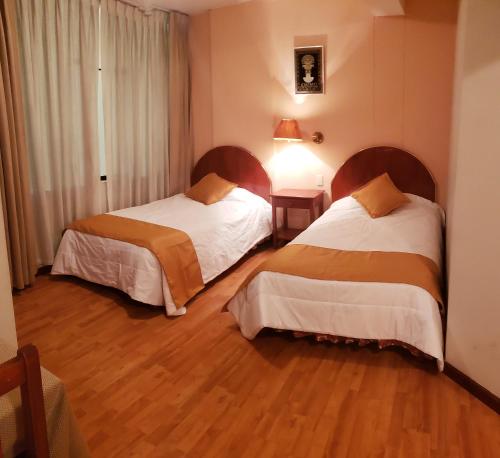 库斯科Vilandré Hotel Cusco的一间卧室设有两张床,铺有木地板