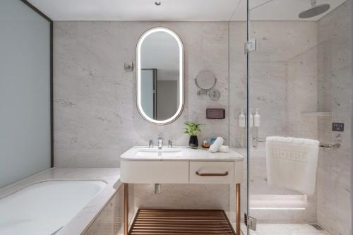 北京北京天伦王朝酒店的一间带水槽、浴缸和镜子的浴室