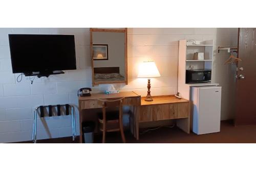 WashburnScotwood Motel by OYO Washburn ND的客房设有书桌、电视和冰箱。