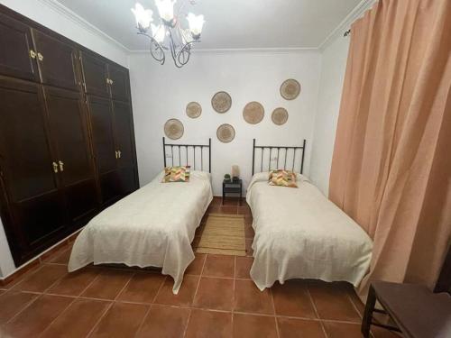 塞维利亚Casa con piscina privada的两张睡床彼此相邻,位于一个房间里