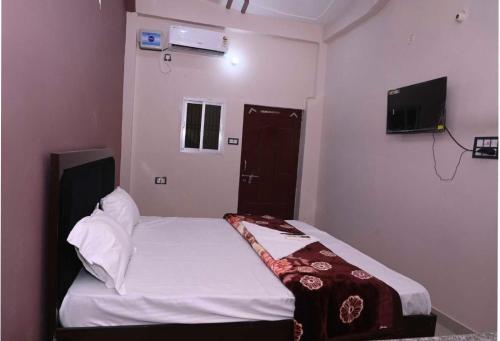AyodhyaOYO Home Om Shanti Palace的一间小卧室,配有一张床和电视