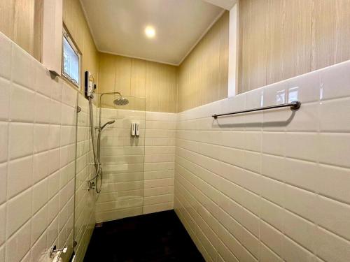 Ban Mo Makluaอาลาแคมป์的带淋浴的浴室和白色瓷砖墙壁