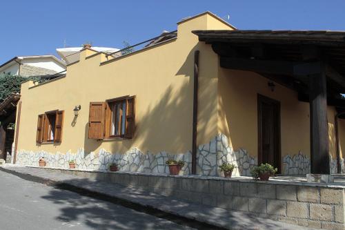 Grotte di CastroAgriturismo Vallesessanta的街上的黄色房子,设有木窗