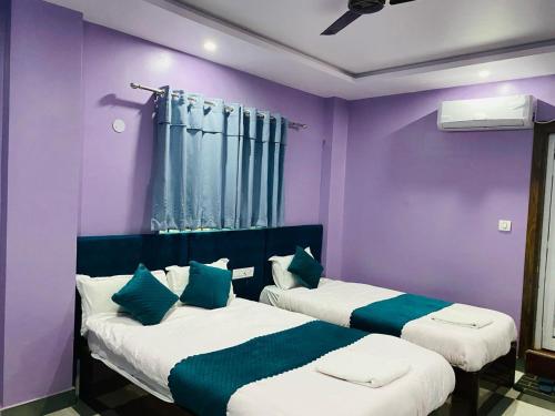 拜拉哈瓦Hotel Mangalam的紫色墙壁客房的两张床