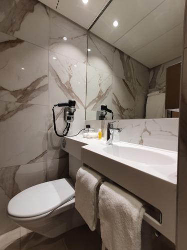 日内瓦纳什机场酒店的一间带水槽、卫生间和镜子的浴室