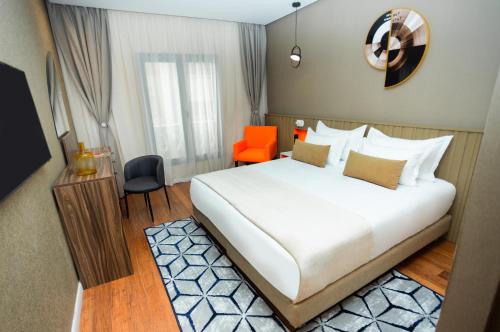 卡萨布兰卡Gray Hotel Casablanca的卧室配有白色大床和橙色椅子