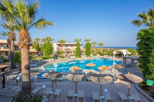 马斯蒂查里Kouros Palace的一个带遮阳伞和椅子的游泳池以及一个度假村