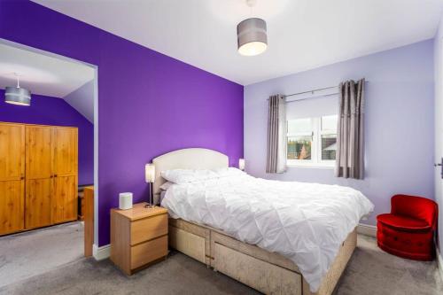 艾尔45 Doonvale Drive的紫色卧室配有一张床和一张红色椅子