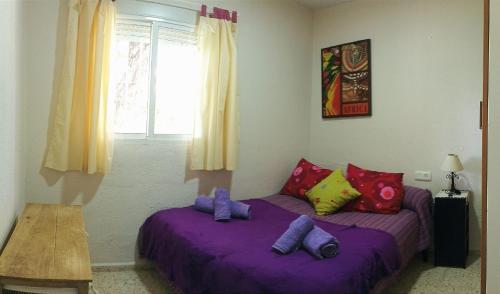 奇克拉纳－德拉弗龙特拉Casa de campo con piscina的一间卧室配有两张带紫色床单和枕头的床。