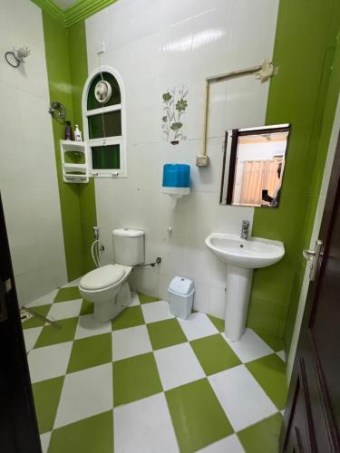 苏尔Orchid sur guest house的绿色和白色的浴室设有卫生间和水槽