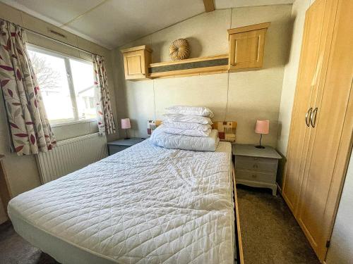 劳斯Superb 6 Berth Caravan At Sunnydale Holiday Park Ref 35079a的一间卧室配有一张带白色床单的床和一扇窗户。