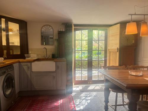 汤顿French Gite Style Garden Apartment, Central Taunton的厨房配有桌子和洗衣机。