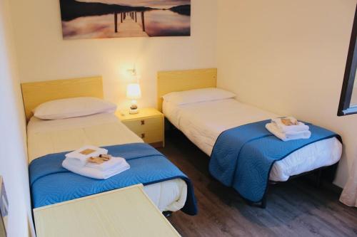卡尔切拉尼卡阿拉戈[Fronte lago]ResidenceGarden, moderno appartamento的一间设有两张床铺和毛巾的房间